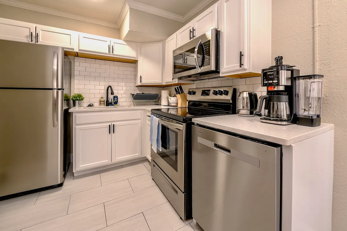 A view of a modern kitchen featuring stainless steel appliances, white cabinetry, a granite countertop, and a central kitchen island. The scene feels welcoming and functional, perfectly suited for both everyday meal preparation and social gatherings.